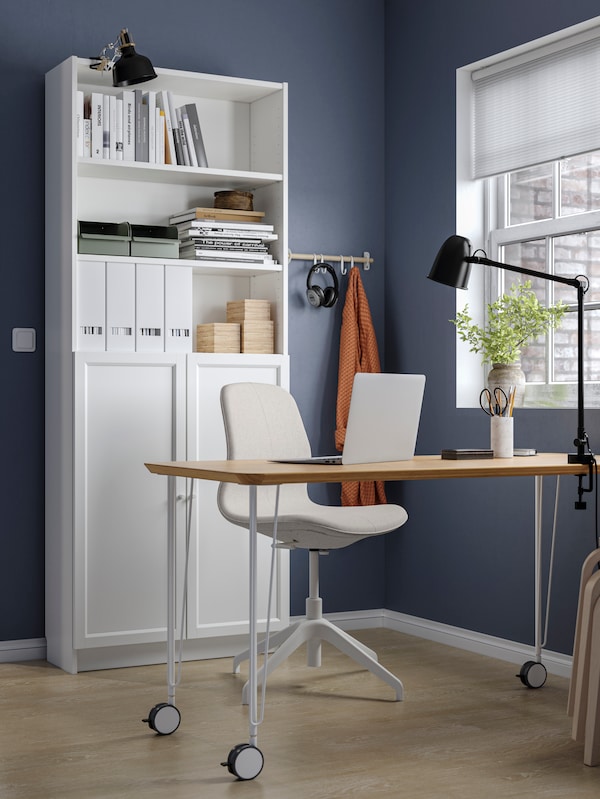 工作区与深蓝色的墙壁,一个ANFALLARE / KRILLE办公桌,LANGFJALL会议椅和比利书柜。