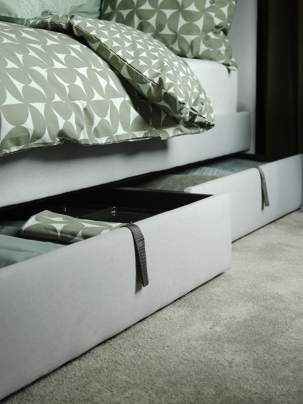 GLADSTAD软垫床上覆盖着ANGSNEJLIKA床单,里面两个露天仓库框下面显示纺织品。
