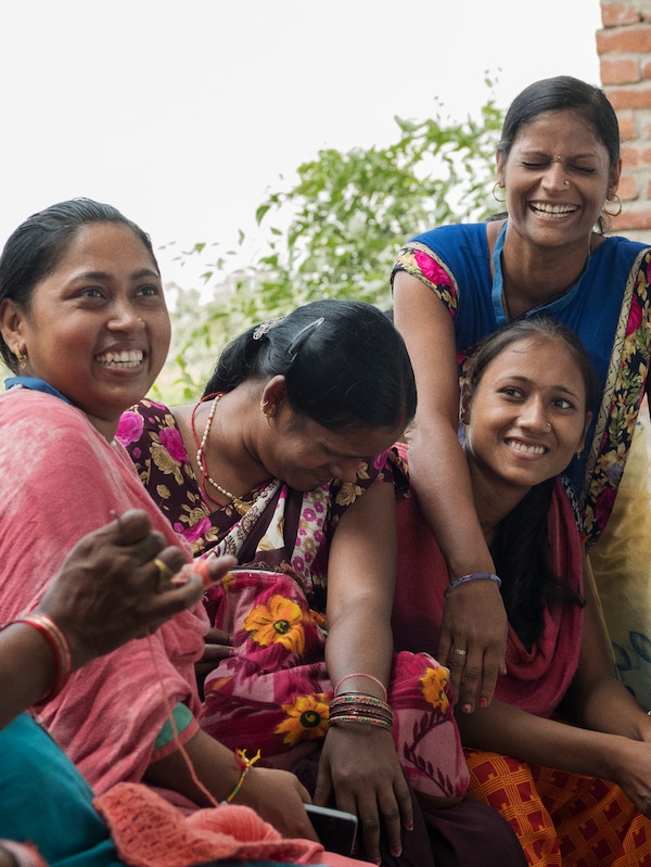 四个印度织工在传统色彩鲜艳的衣服和珠宝,享受外面笑。