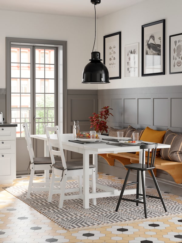 白色NORDVIKEN桌子有三把椅子,黑色吊灯上面的角落里的厨房门。