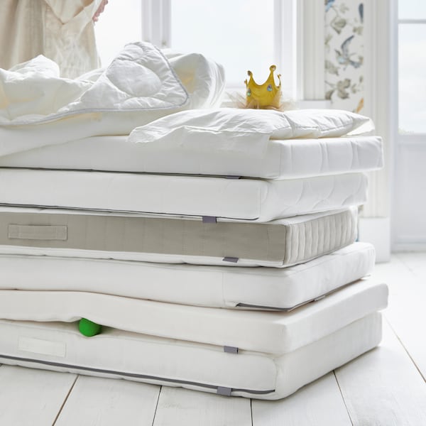 很多床床垫都堆放在地板上的羽绒被,一个枕头和一个玩具皇冠。