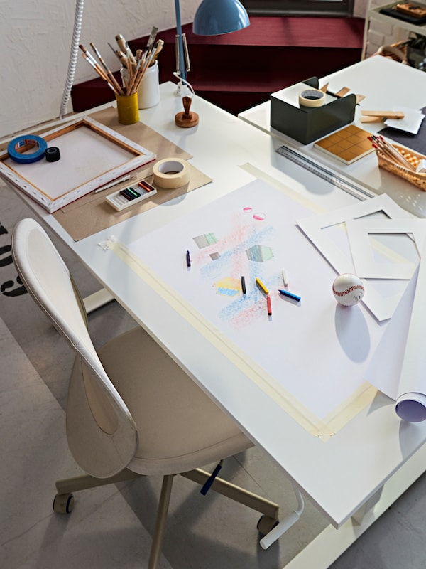 一个FLINTAN TROTTEN桌子办公椅。桌面有配件,笔和纸满是草图。