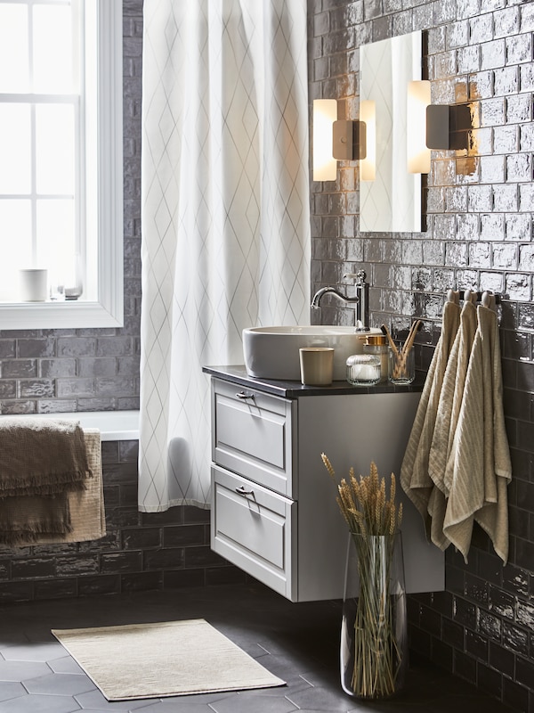 一个浴室和一个白色/灰色/米色BASTSJON浴帘,+浅灰色/棕色和浅肤色的手,浴巾。