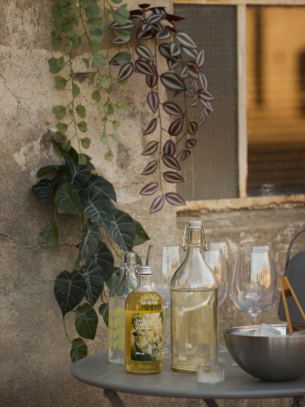 FEJKA人工植物装饰墙。DRYCK弗拉德接骨木花糖浆和KORKEN瓶子在桌子上的墙。