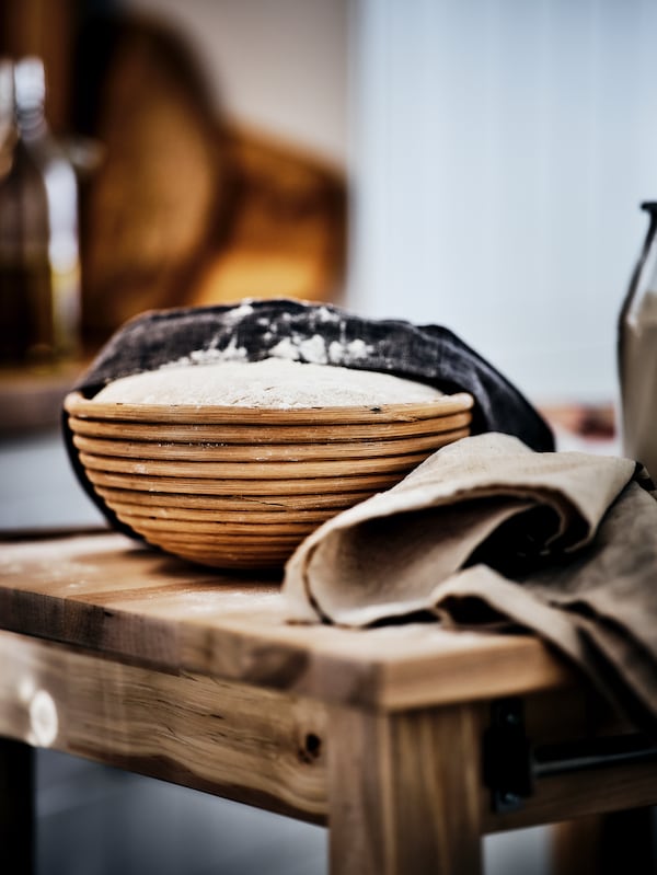 防的木桌上篮子装满面包面团。茶巾是拖过一半的面团。