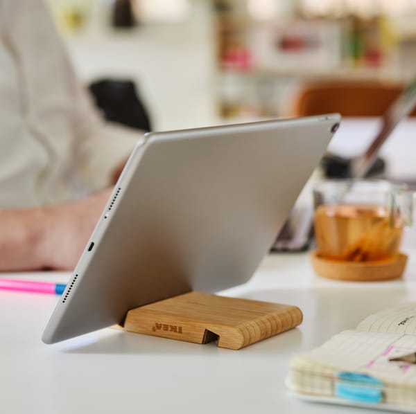 竹卑尔根夹手机/平板电脑坐在桌子附近拿着平板电脑日记,一支笔和一个杯子。
