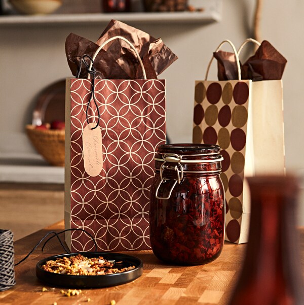 黑色和橡木色的VADHOLMA厨房岛台，混合颜色的KRÖSAMOS礼品包和红棕色盖子的KRÖSAMOS罐子。