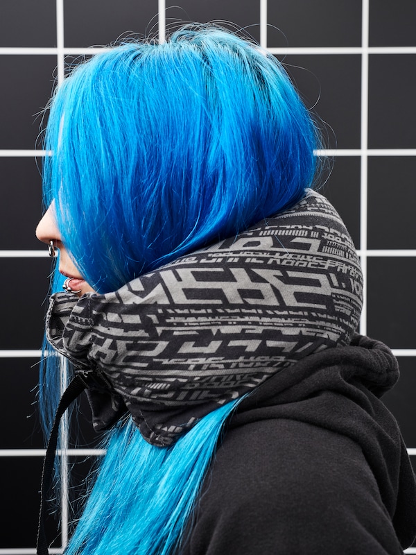 特写一个女人的形象。她有明亮的蓝色头发和黑色连帽衫,戴着LANESPELARE脖子枕头。