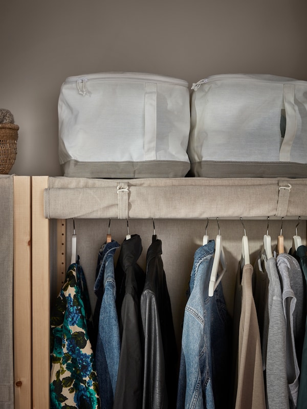 一个最小与织物百叶窗打开衣柜。里面的衣服。上面两个最小的织物存储盒。