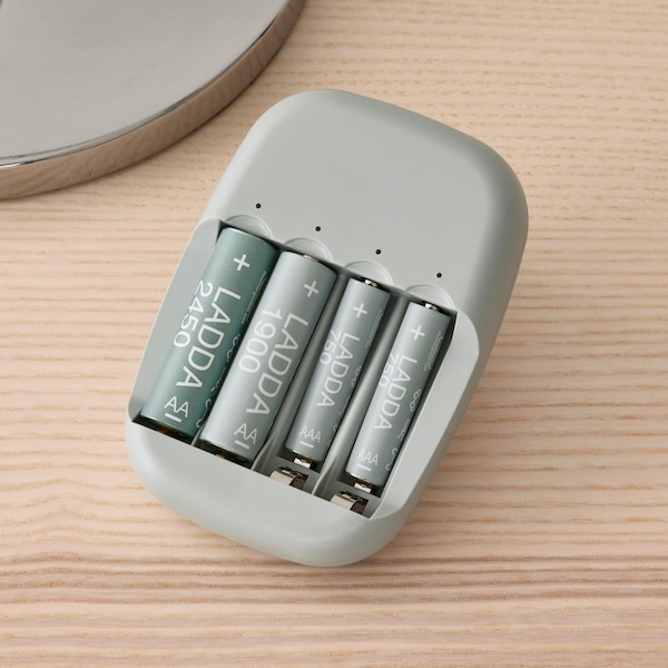 四个LADDA充电电池STENKOL电池充电器插入一个套接字在白色的墙壁上。