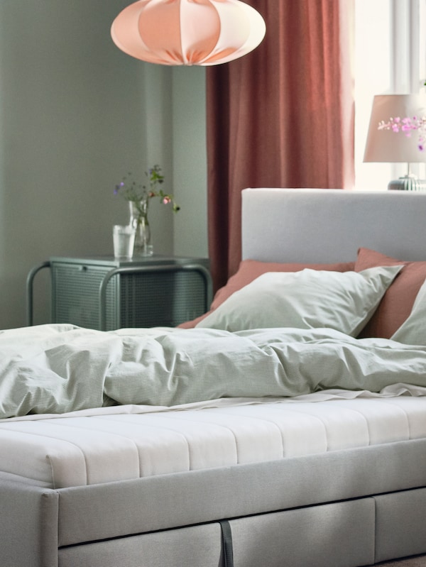 GLADSTAD软垫床上存储盒和一个ASVANG泡沫床垫站在卧室靠近窗户。