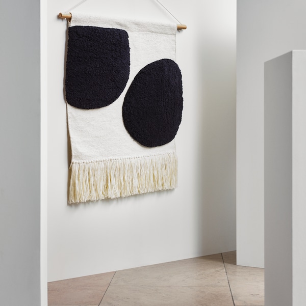 BLANDSKOG挂tapestry特性两个黑圈在一个米色背景,和挂在一个普通的白墙。