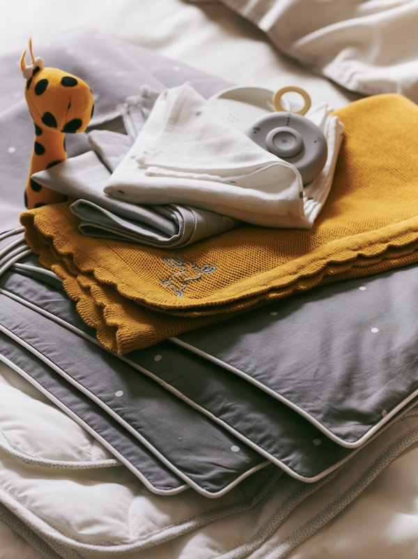 SOLGUL毯与各式各样的深黄色婴儿纺织品在灰色和白色一起一个小毛绒玩具。