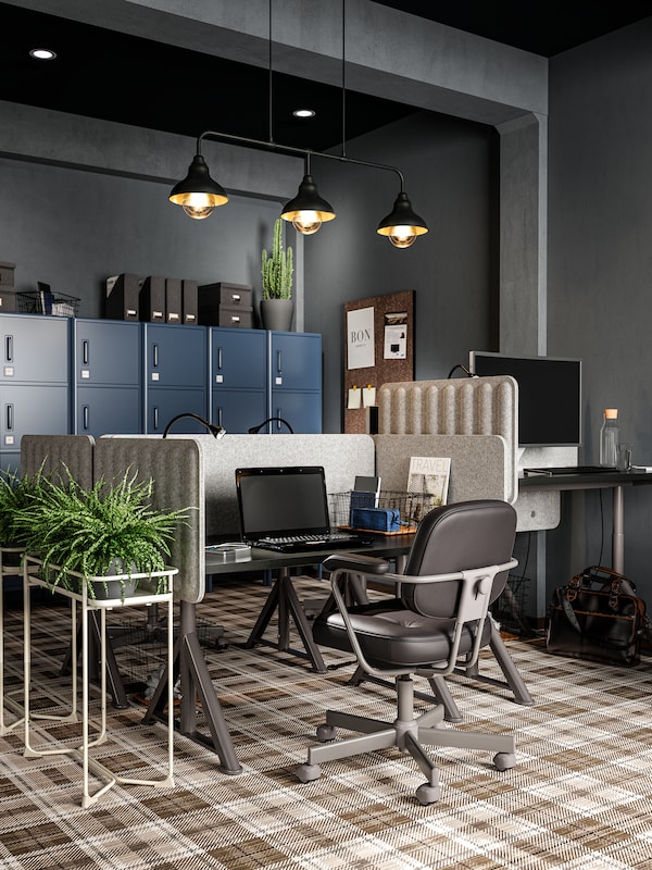 工作区除以感觉屏幕,一个皮革会议椅,一个黑色的笔记本电脑,三个黑色的吊灯,一个工厂。