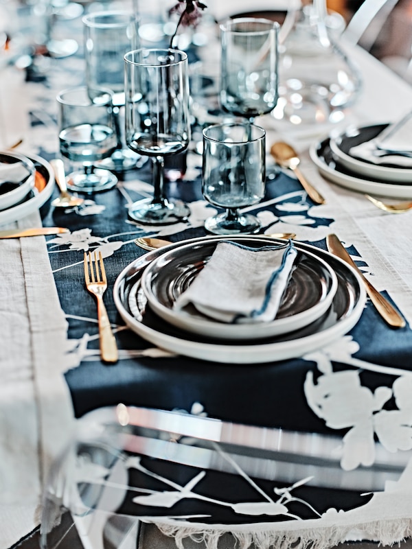 桌上铺着金属色泽TILLAGD 24-piece餐具,深灰色OMBONAD端盘子,盘子和OMBONAD眼镜。