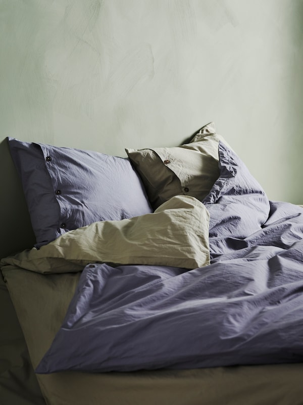 的KRAKRISMOTT被套和枕套绿色和蓝色是在床上,看起来柔软舒适。