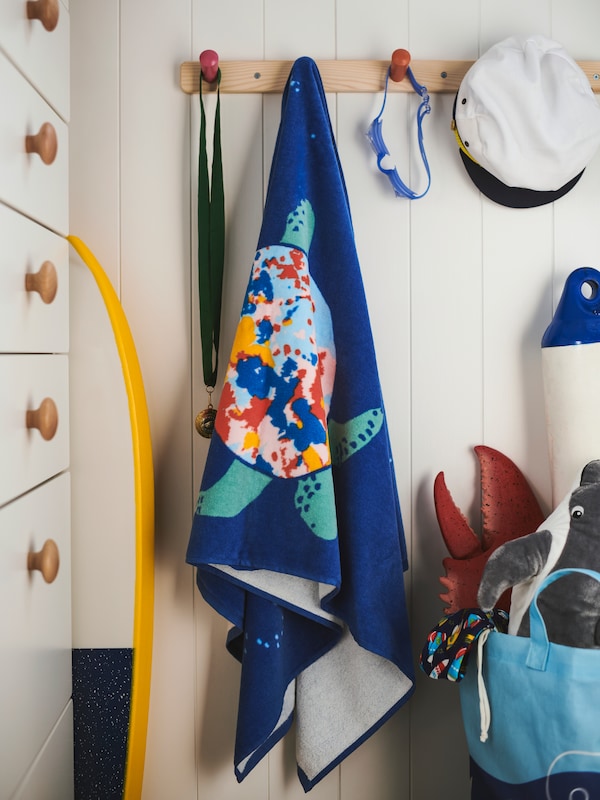BLAVINGAD浴巾,一个水手的帽子和其他物品从FLISAT旋钮挂架4旋钮安装在一个木制墙壁。