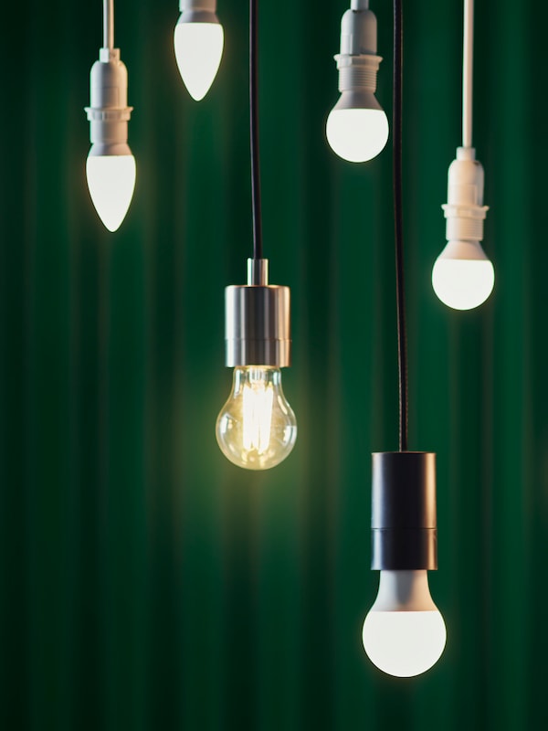 6个不同设计的LED灯泡悬挂在不同的高度，背景是墨绿色的窗帘。