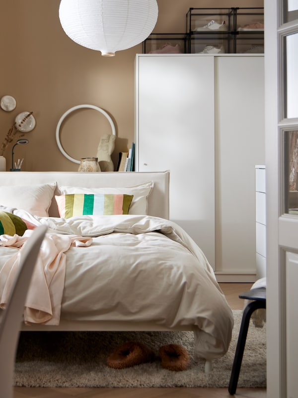 白色与ANGSLILJA KLEPPSTAD床床单站在白人面前KLEPPSTAD与滑动门衣柜。