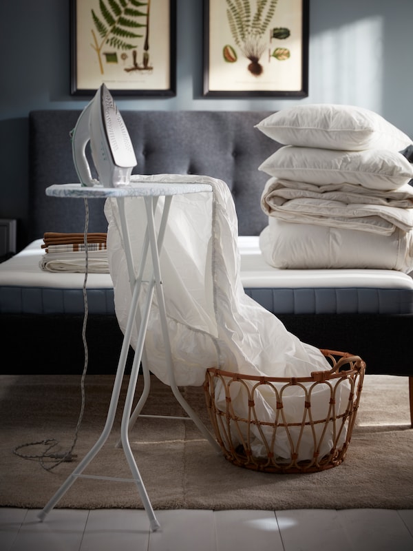 白色NATTJASMIN床套和铁的白色拉特烫衣板,加上一堆白色的床上用品的床上。
