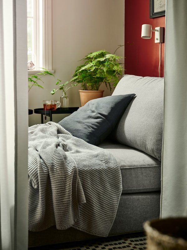 浅灰色INGABRITTA扔和垫在一个灰色MAJBRAKEN靠垫躺在一个米色/灰色KIVIK躺椅。