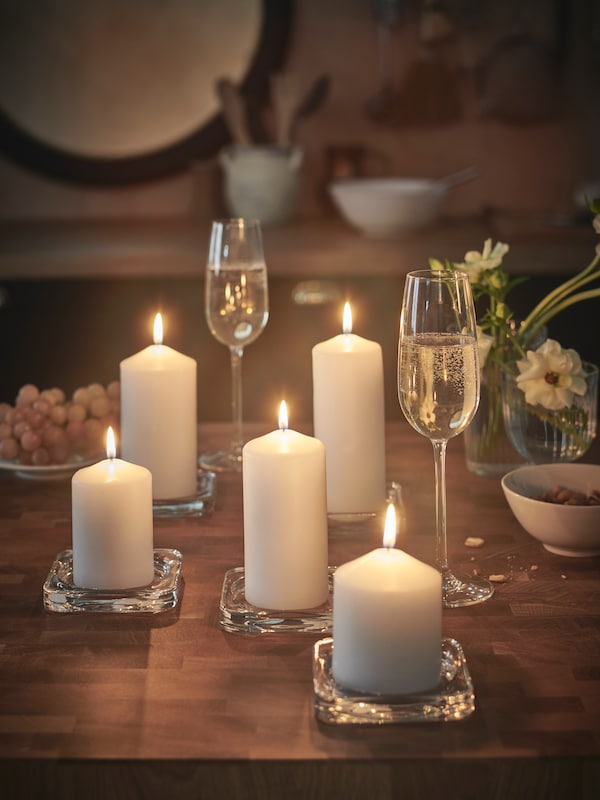 一组五块FENOMEN无味蜡烛,每在一个透明玻璃GLASIG蜡烛碟在餐桌上。