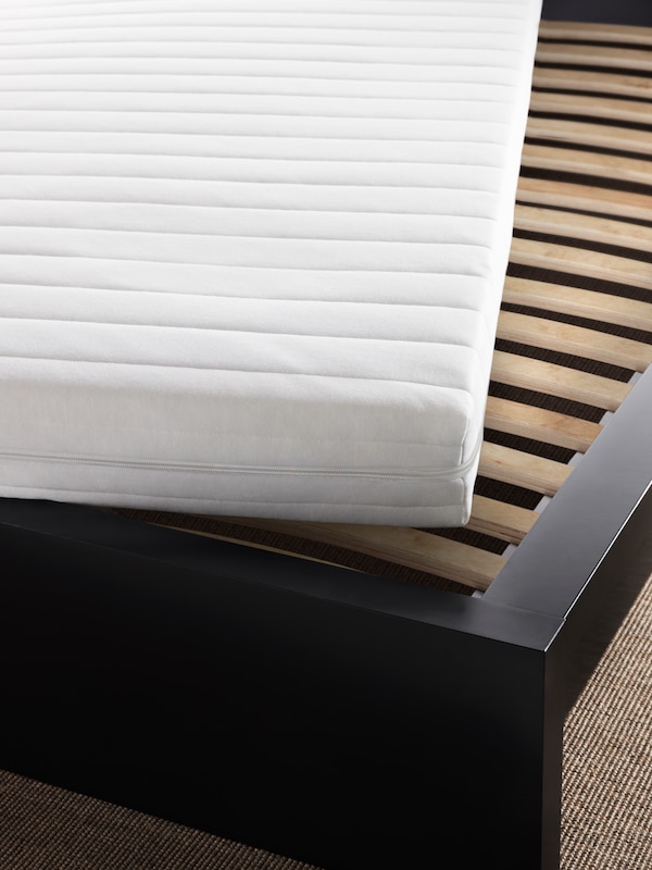 床的黑褐色框架和一个白色的床垫在一个角度上揭示LUROY摔下床。