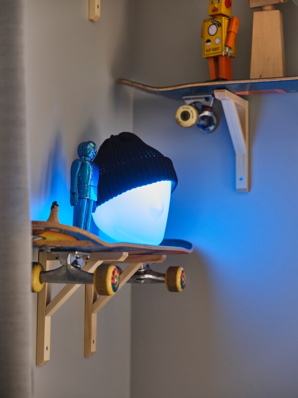ISKARNA LED台灯和一顶帽子上站在架子上由一个滑板在角落里附近的一个类似的架子上。
