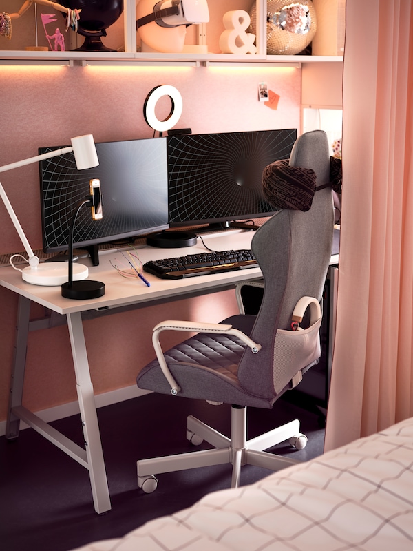 灰色UTESPELARE游戏椅在浅灰色的办公桌前拿着两个显示器,一个台灯,一个环形光和键盘。