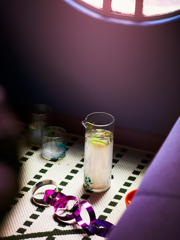 一个OMSESIDIG玻璃水瓶在清晰和绿色玻璃装满柠檬水,旁边两个OMSESIDIG眼镜在不同大小。