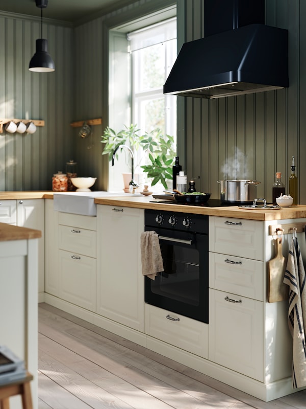 白色与BODBYN METOD厨房抽屉面板,MATTRADITION强迫空气炉黑,挂灯和植物。