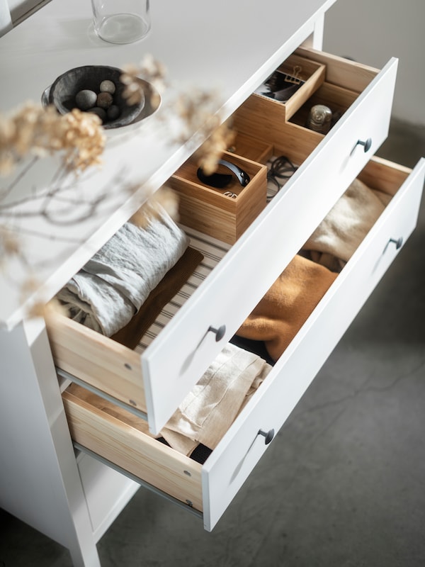 白色的彩色HEMNES有3个抽屉的柜子和两个包含折叠衣服,小盒子打开抽屉。