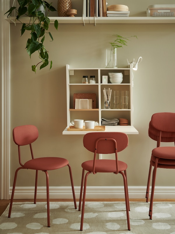 Brown-red OSTANO椅子放置圆形白色NORBERG固定在墙上的活动翻板表存储满了餐具。
