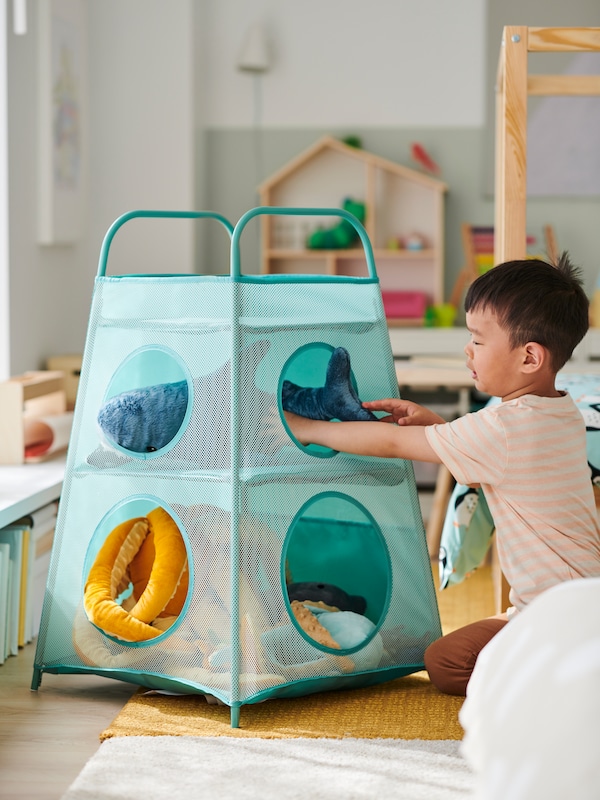 一个孩子将一个毛绒玩具鲨鱼的顶级TIGERFINK存储隔间,上面的黄色的地毯。