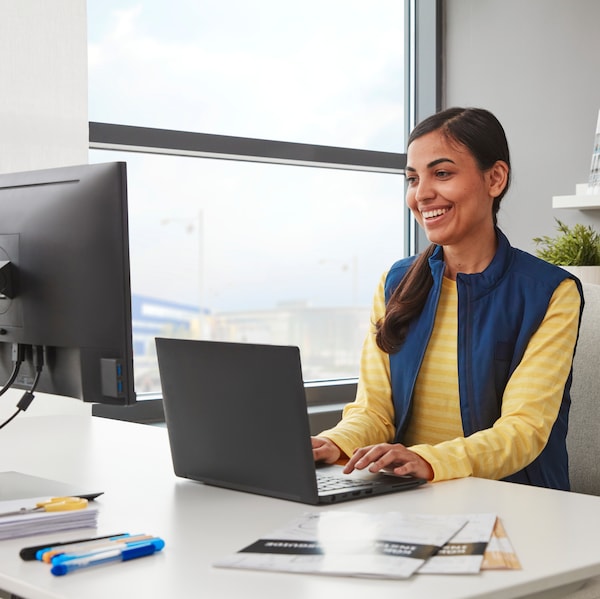 Une femme est assise à un bureau avec un ordinateur de bureau et unordinateur便携。