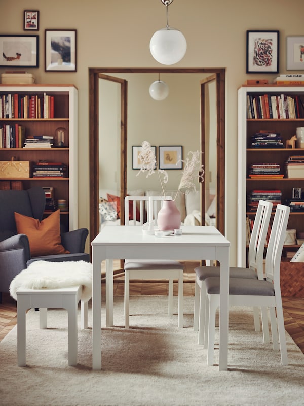 白色EKEDALEN可扩展表,三个EKEDALEN椅子和一个EKEDALEN板凳在舒适的房间里有很多书。