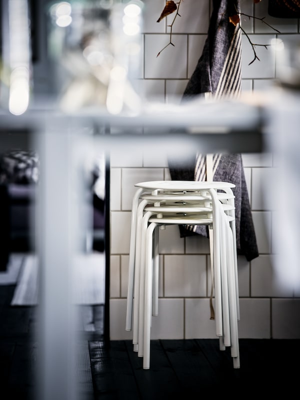 堆白色马吕斯凳子站在白墙在black-and-white-themed厨房。