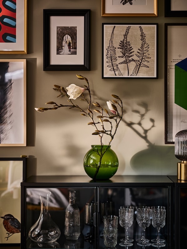 在einem sparlich beleuchteten Raum steht一张grune KONSTFULL花瓶auf einem双门衣柜。Schatten spielen der魔杖。