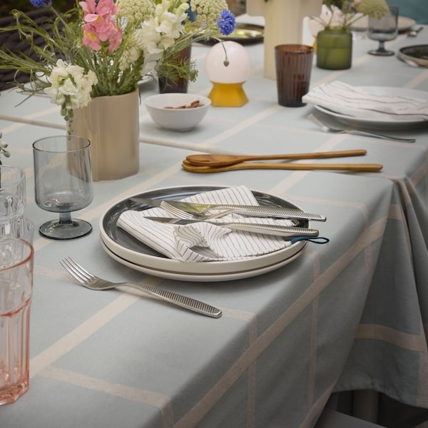 夏天表设置,各种花瓶坐在桌子上满是colorsful鲜花,设置不同的餐具和餐具上白色的桌布。