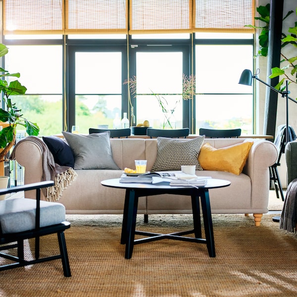 一个通风的客厅黑KRAGSTA咖啡桌上放置的浅肤色VISKAFORS三人沙发上。