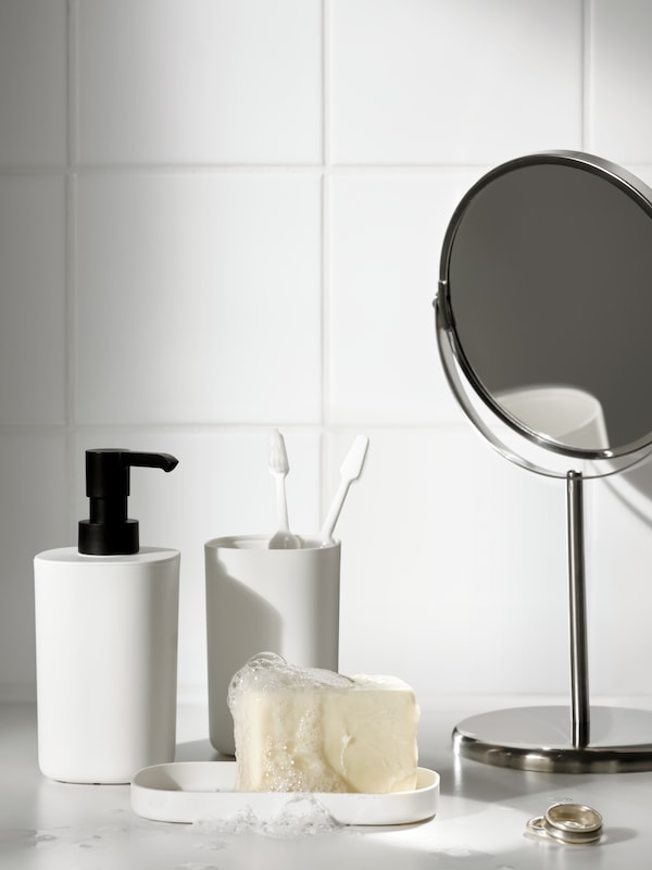 一个白色给皂器,托盘和牙刷架的STORAVAN浴室镜子旁边。