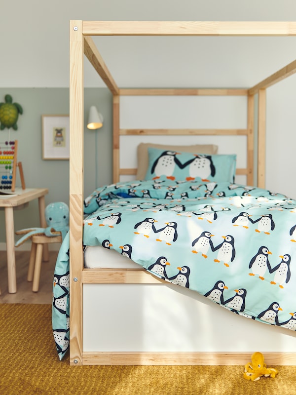 库那可逆的床与BLAVINGAD床单和企鹅模式站在卧室黄色LANGSTED地毯。