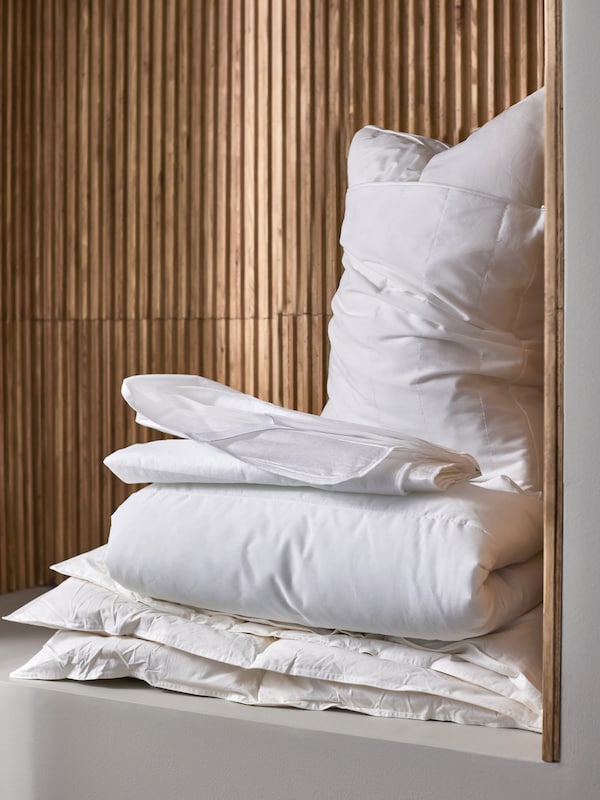 一堆床上用品包括与LUDDROS枕一个枕头保护者和TAGELSAV床垫保护对一个木制墙壁。