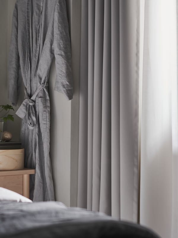 灰色晨衣挂在墙上一个浅灰色MAJGULL房间变暗幕附近BJORKSNAS床头柜。