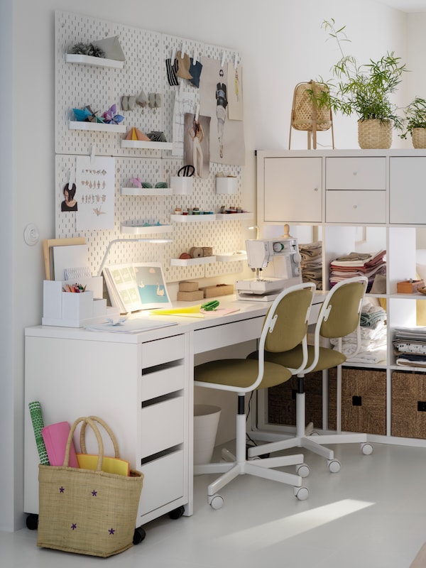 工作区与白色色调由一个白色的桌子,两个旋转的椅子和一个书架单元用作房间隔板。