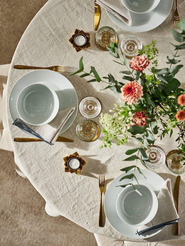 圆桌与一组自然OMBONAD台布白色宜家365 +的餐盘和碗,金属色泽餐具+花朵。亚博平台信誉怎么样