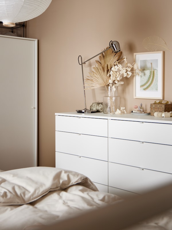 两个白人VIHALS衣柜4站在卧室的墙上,MODERMOLN工作灯,一个花瓶和其他物品。