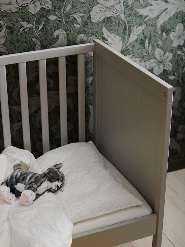LILLEPLUTT软玩具猫是灰色与LENAST SUNDVIK床床单。床的一侧。