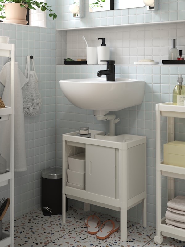 一个白色LILLTJARN / SKATSJON浴室家具镶嵌黑色SALJEN水龙头。一扇门打开内阁显示框。