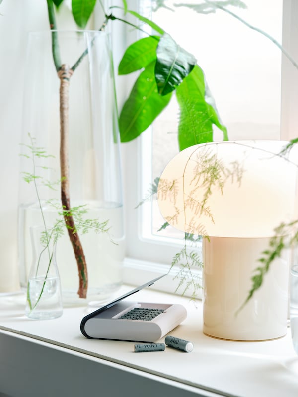 LADDA充电电池在一个窗口面板DEJSA台灯明亮和通风的房间,绿色植物的背景